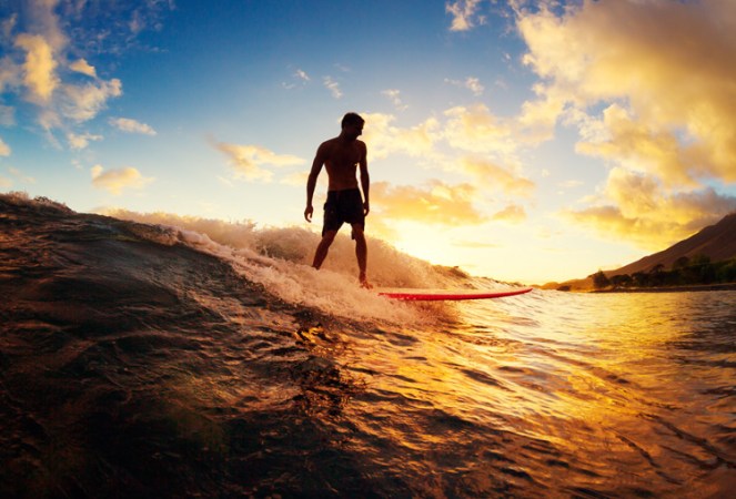Surfing at Sunset. Young Man Riding Wave at Sunset. Outdoor Acti